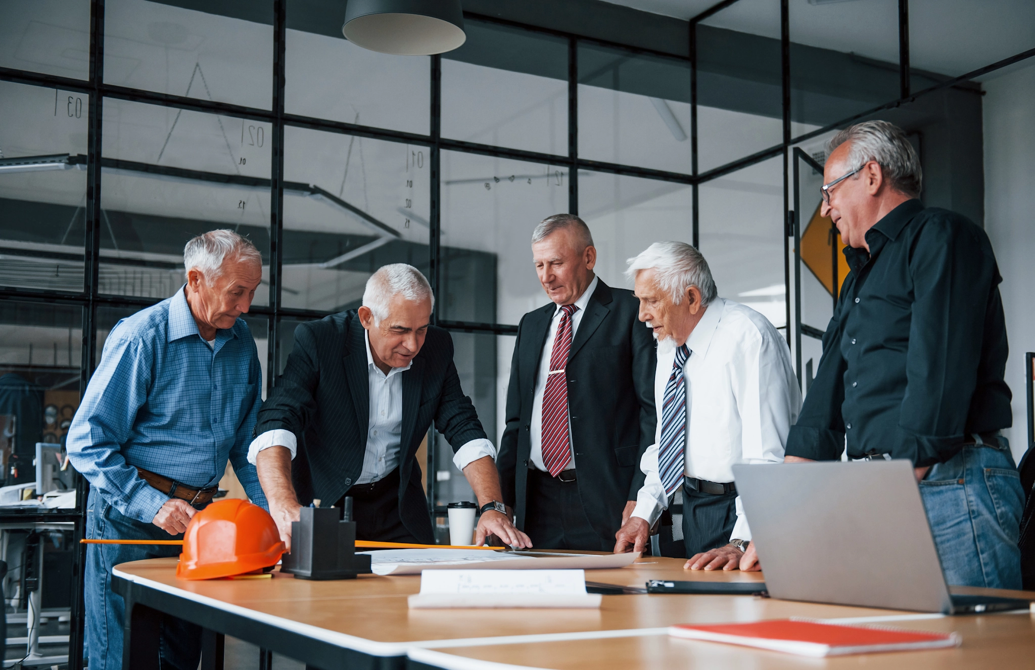 Ein Team älterer Geschäftsleute und Architekten arbeitet im Büro an einem Plan – steht für Zusammenarbeit und gemeinsames Planen.